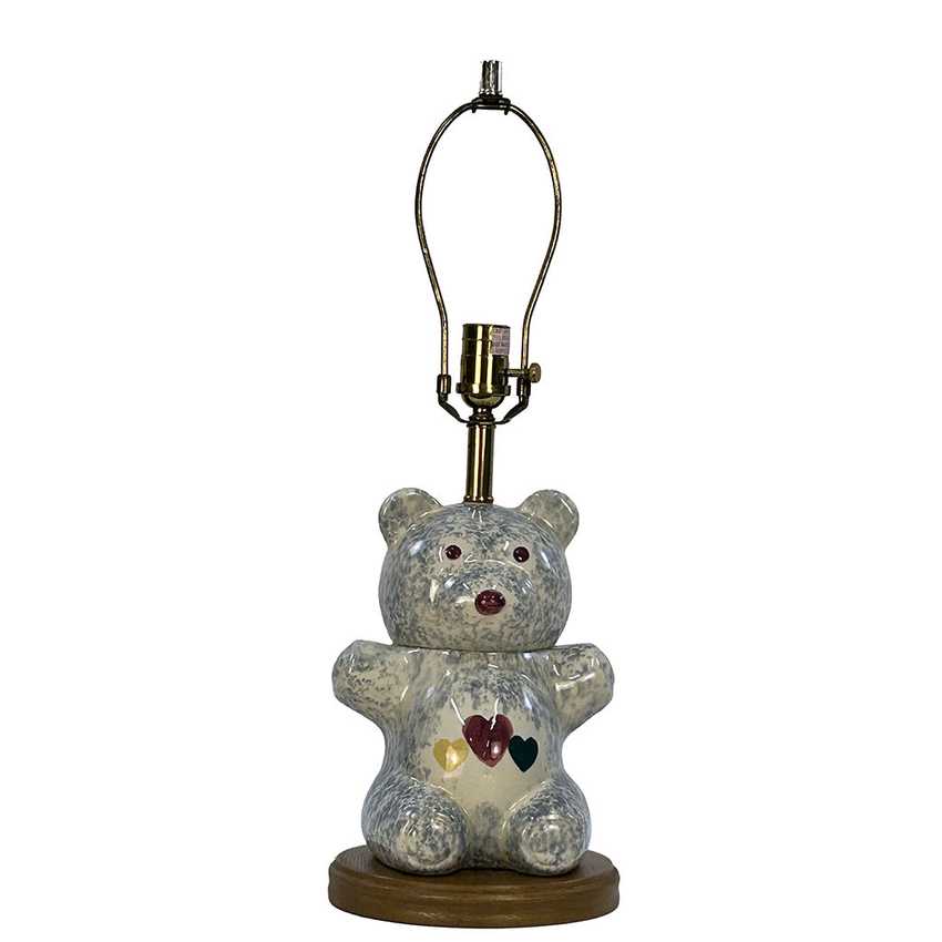 A ceramic teddy bear table lamp with a speckled gray and white glaze, featuring small red eyes, a red nose, and three small heart accents on its chest. The lamp has a brass-colored metal neck and a brown wooden base, set against a plain white background.