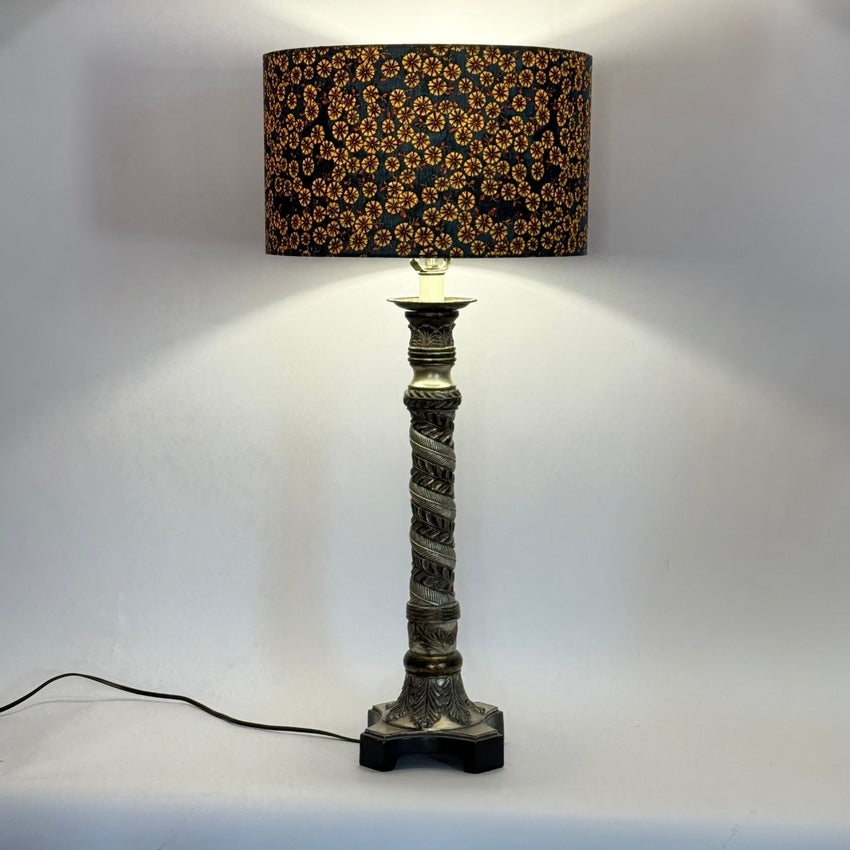 Decorative tall table lamp with a patterned shade on a plain background