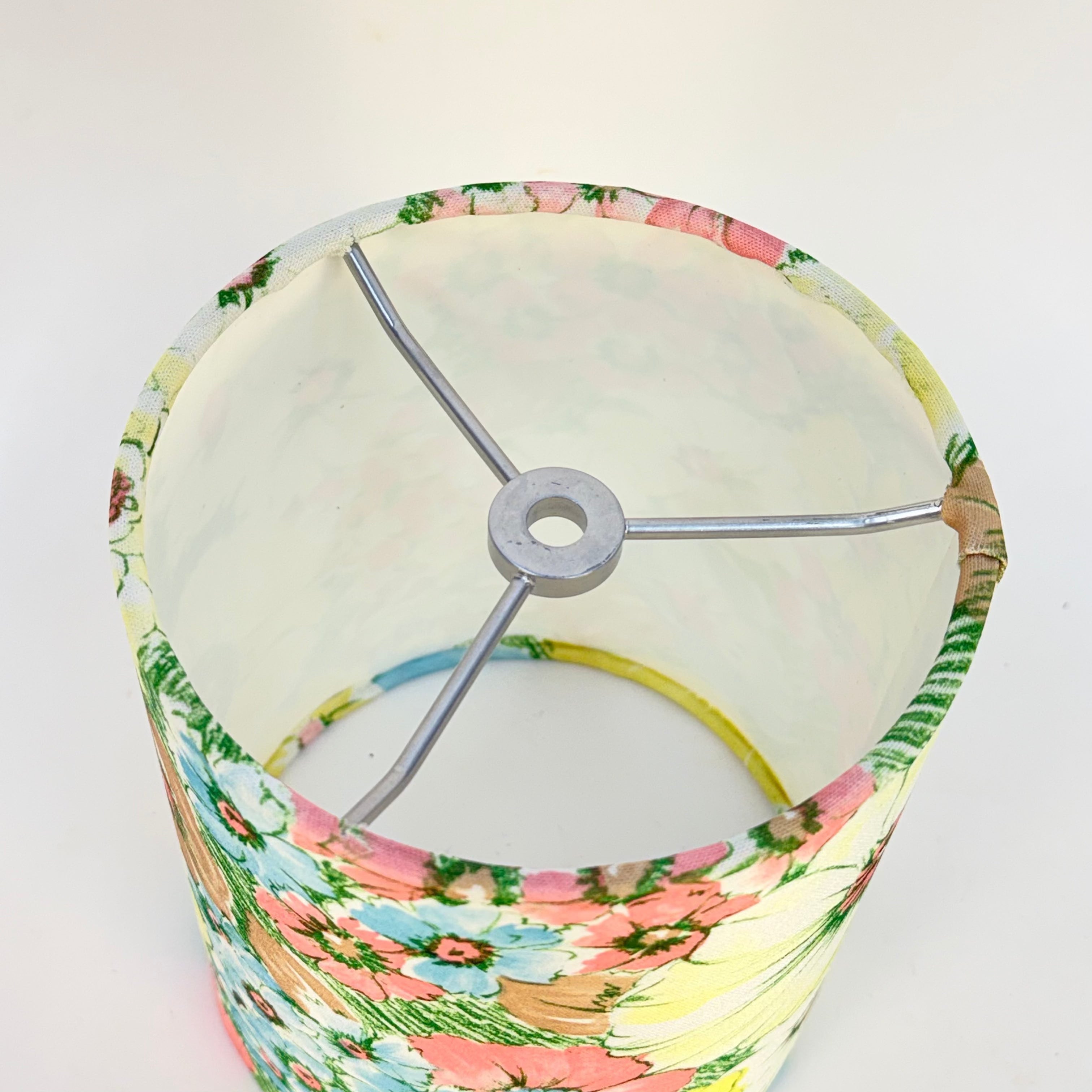 Floral-patterned lampshade with a metallic fixture on a white background